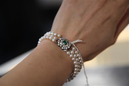 A French triple strand graduated cultured pearl bracelet with 18ct gold and platinum, emerald and diamond set clasp, 18.5cm.